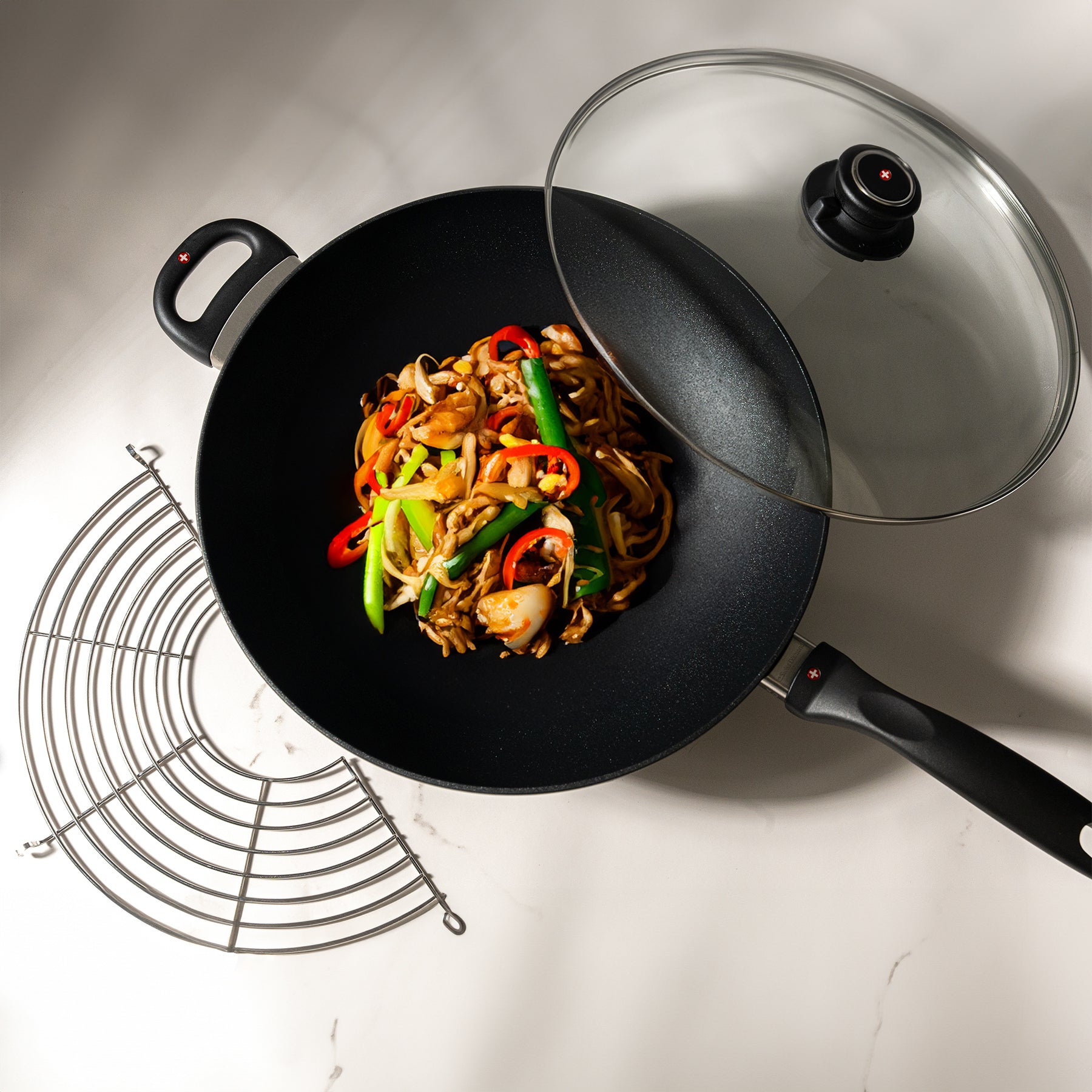 XD Nonstick 28 cm Wok with Glass Lid Top View with food inside and rack on the side on kitchen counter