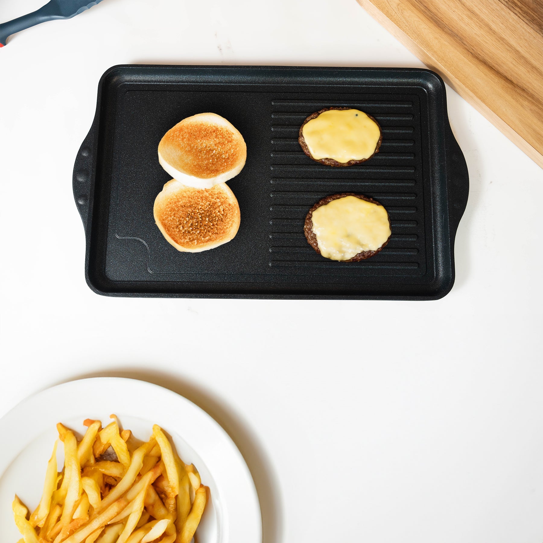 XD Nonstick 118 cm x 28 cm Double-Burner Grill/Griddle Combo in use with food on pan